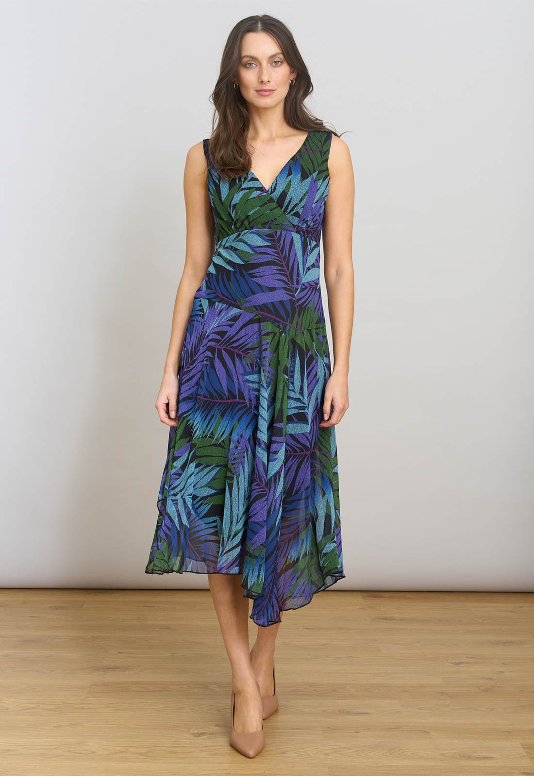Woman wearing a blue and green leaf-patterned dress on a plain background