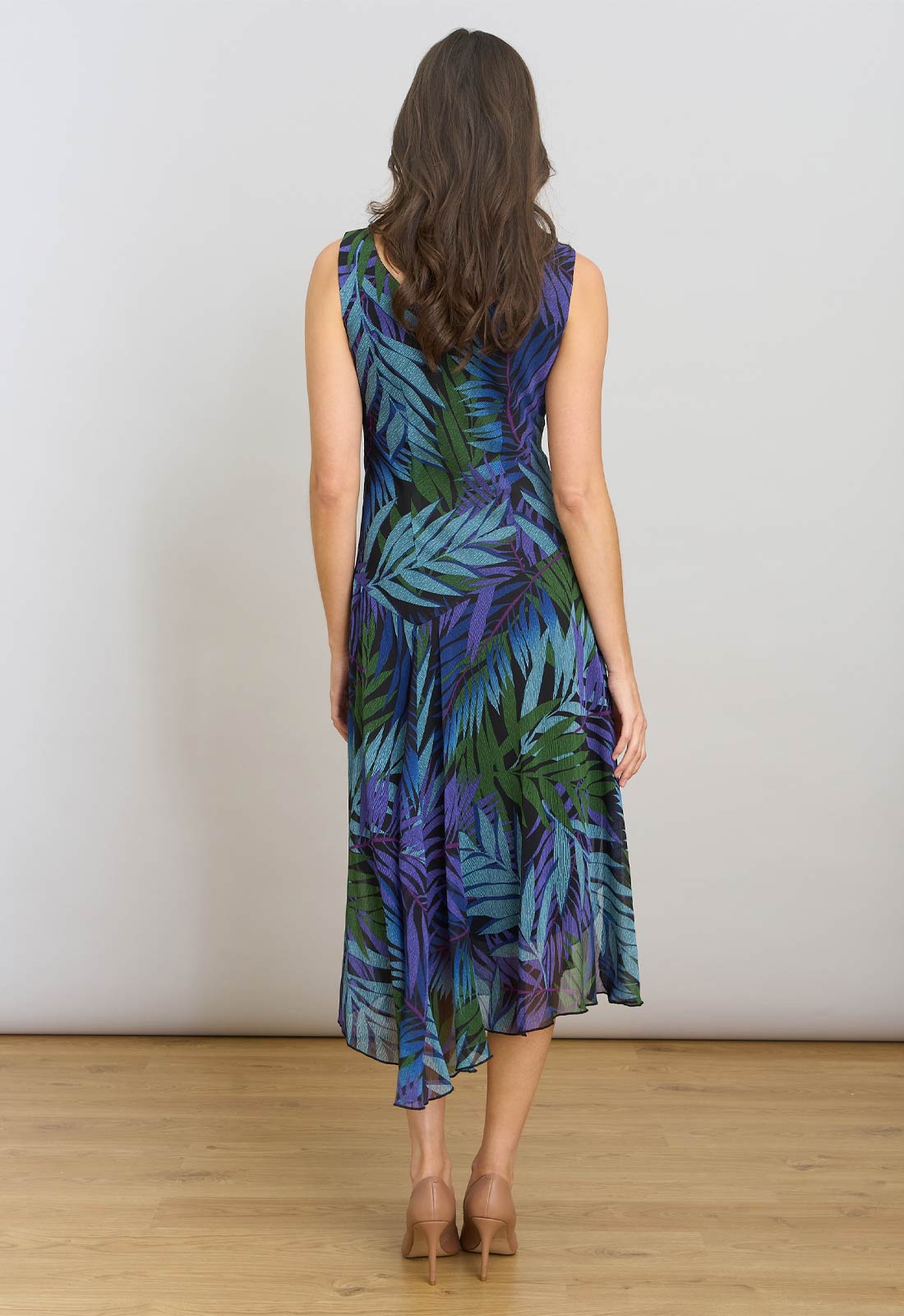Woman wearing a sleeveless dress with a tropical leaf pattern against a plain background
