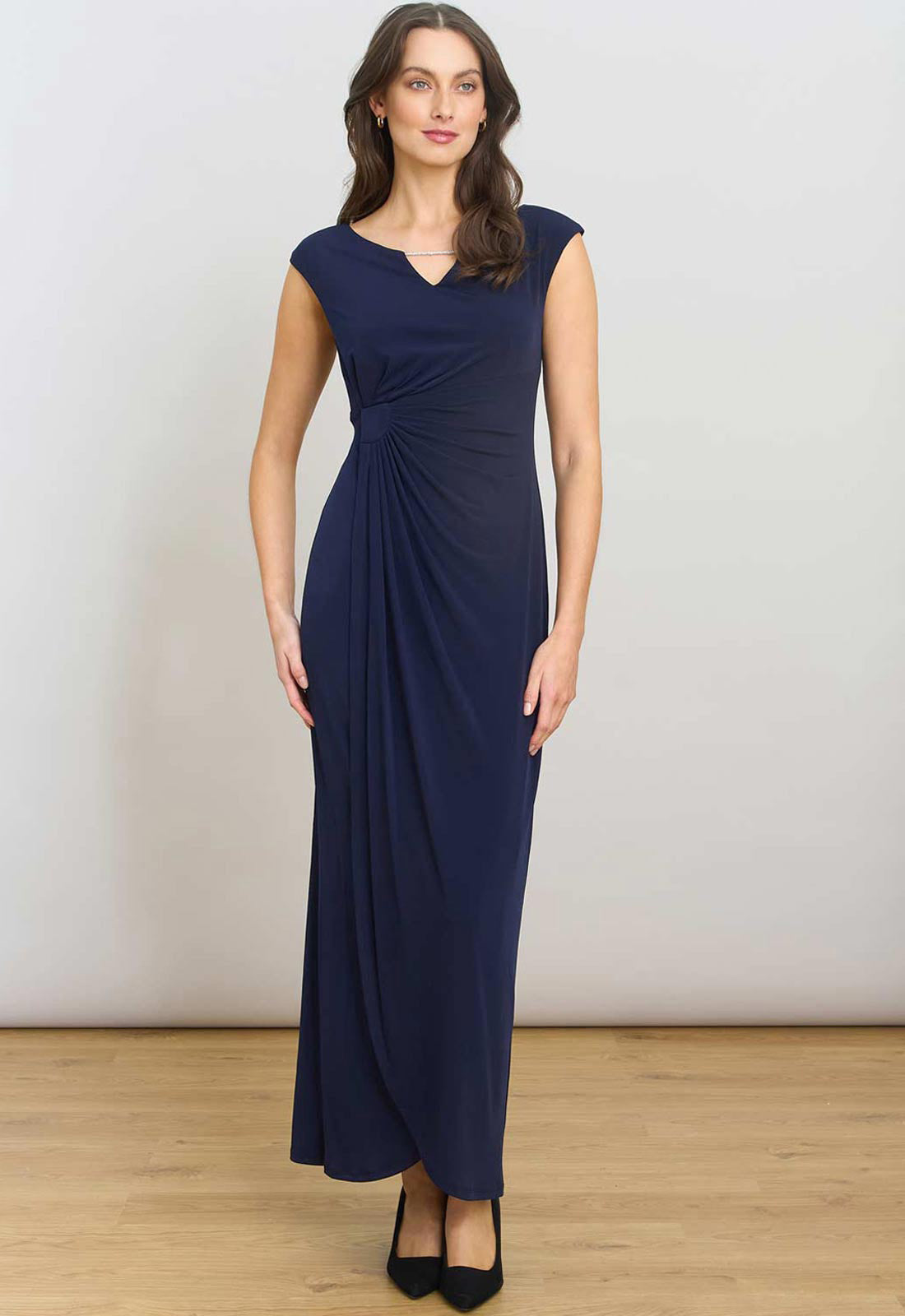 Woman wearing a navy blue evening gown against a plain background