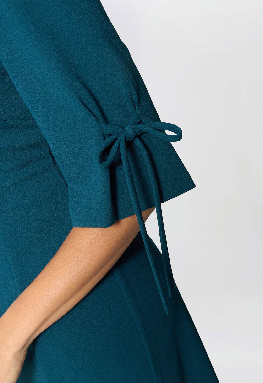 Teal dress with a tie detail on a white background