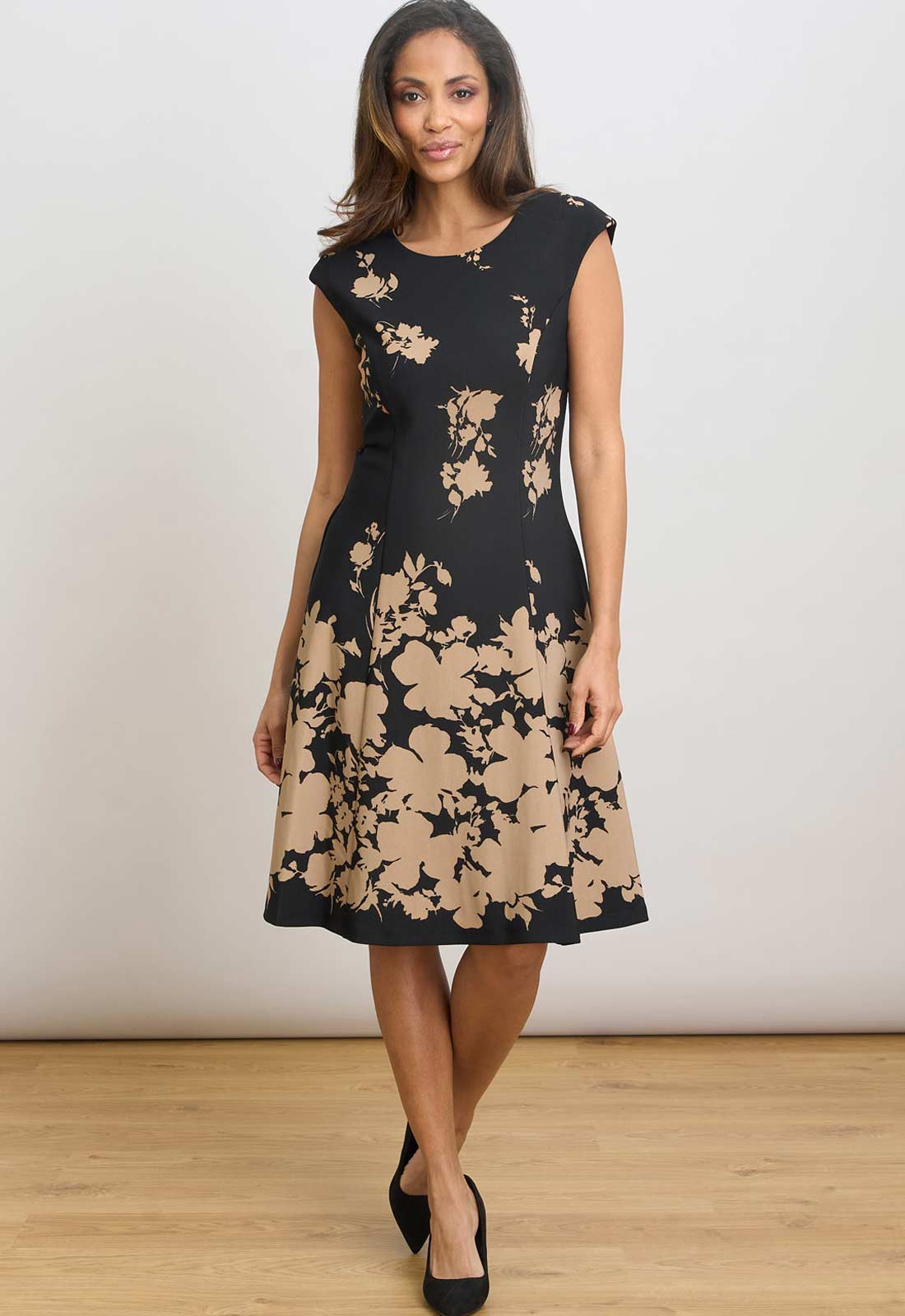 Woman wearing a black dress with beige floral pattern on a white background