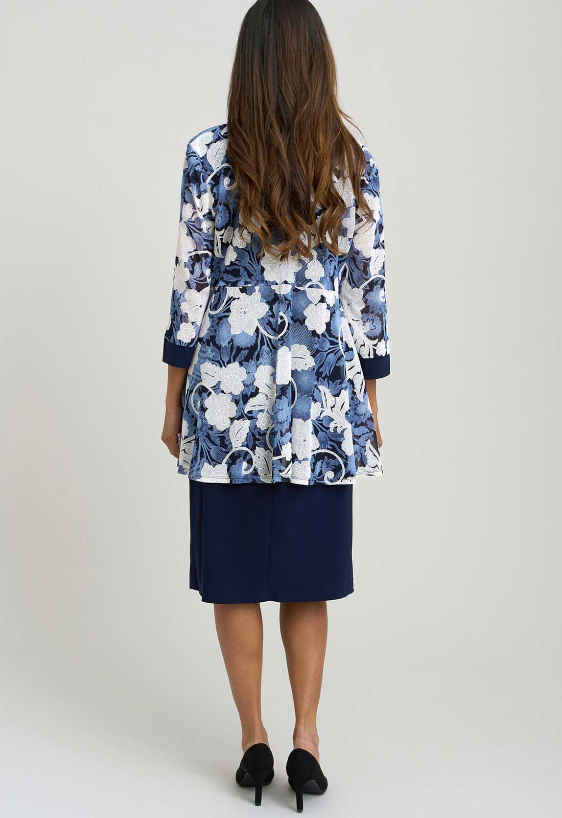 Woman wearing a blue floral jacket and navy skirt on a white background