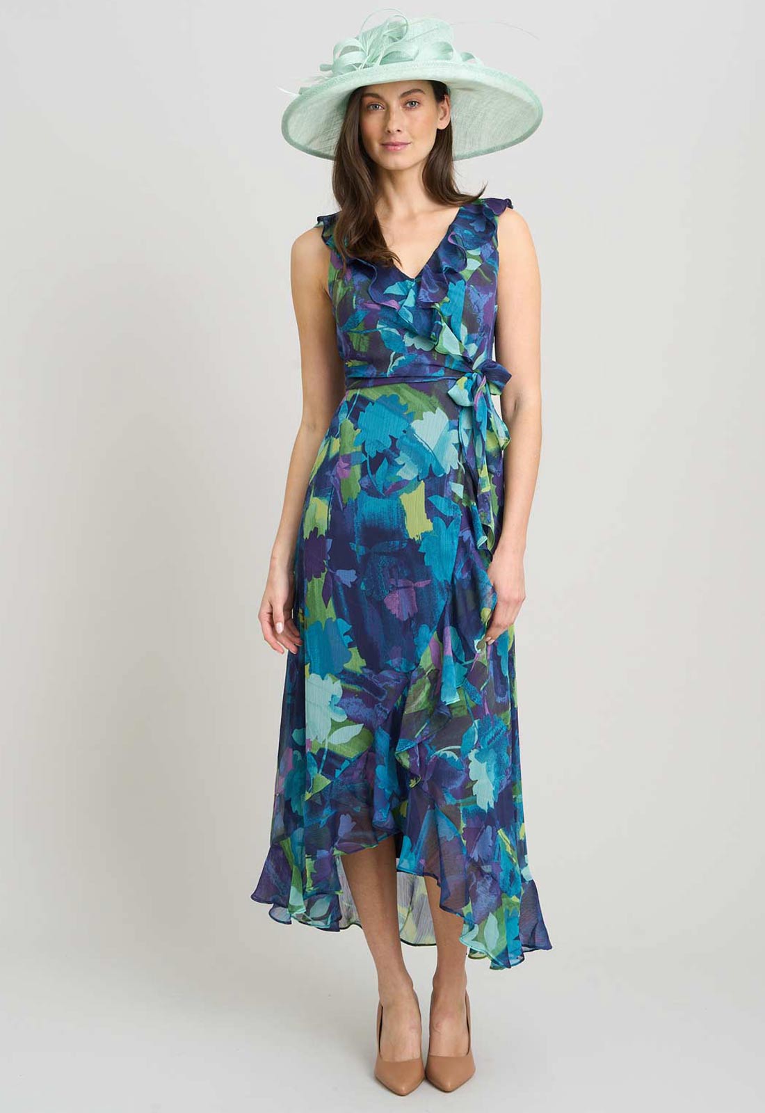 Woman wearing a floral dress and hat on a plain background