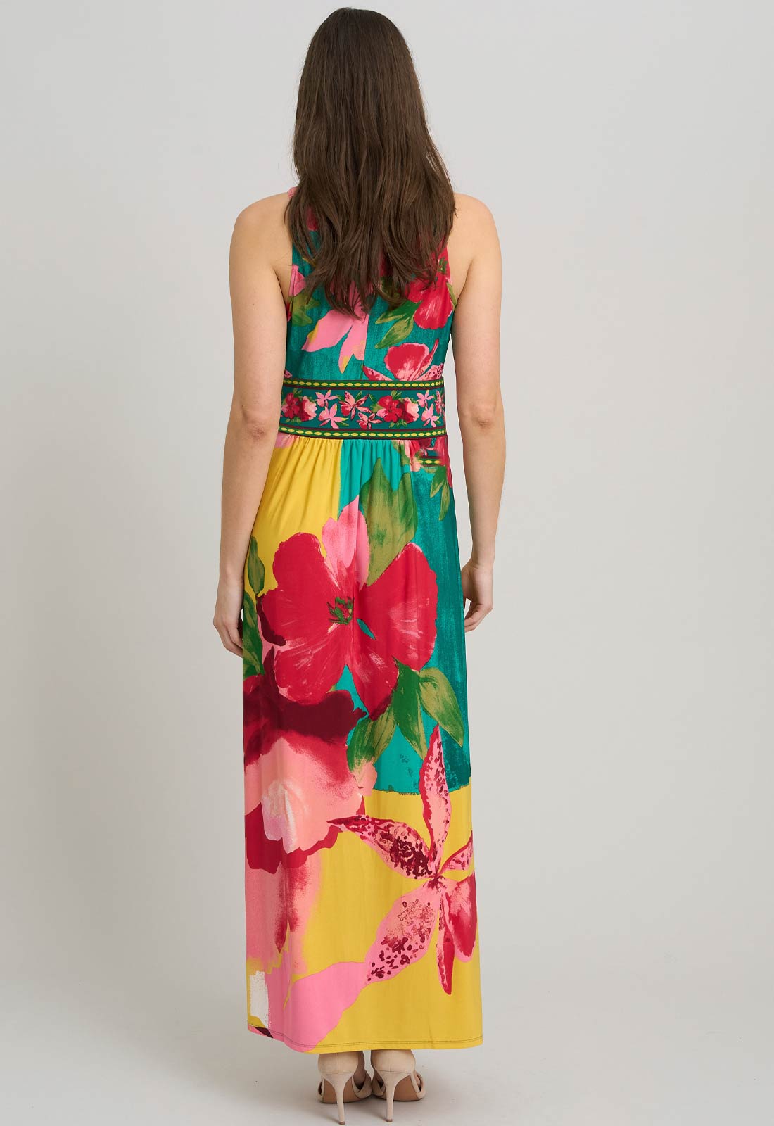 Woman wearing a colorful floral dress on a plain background
