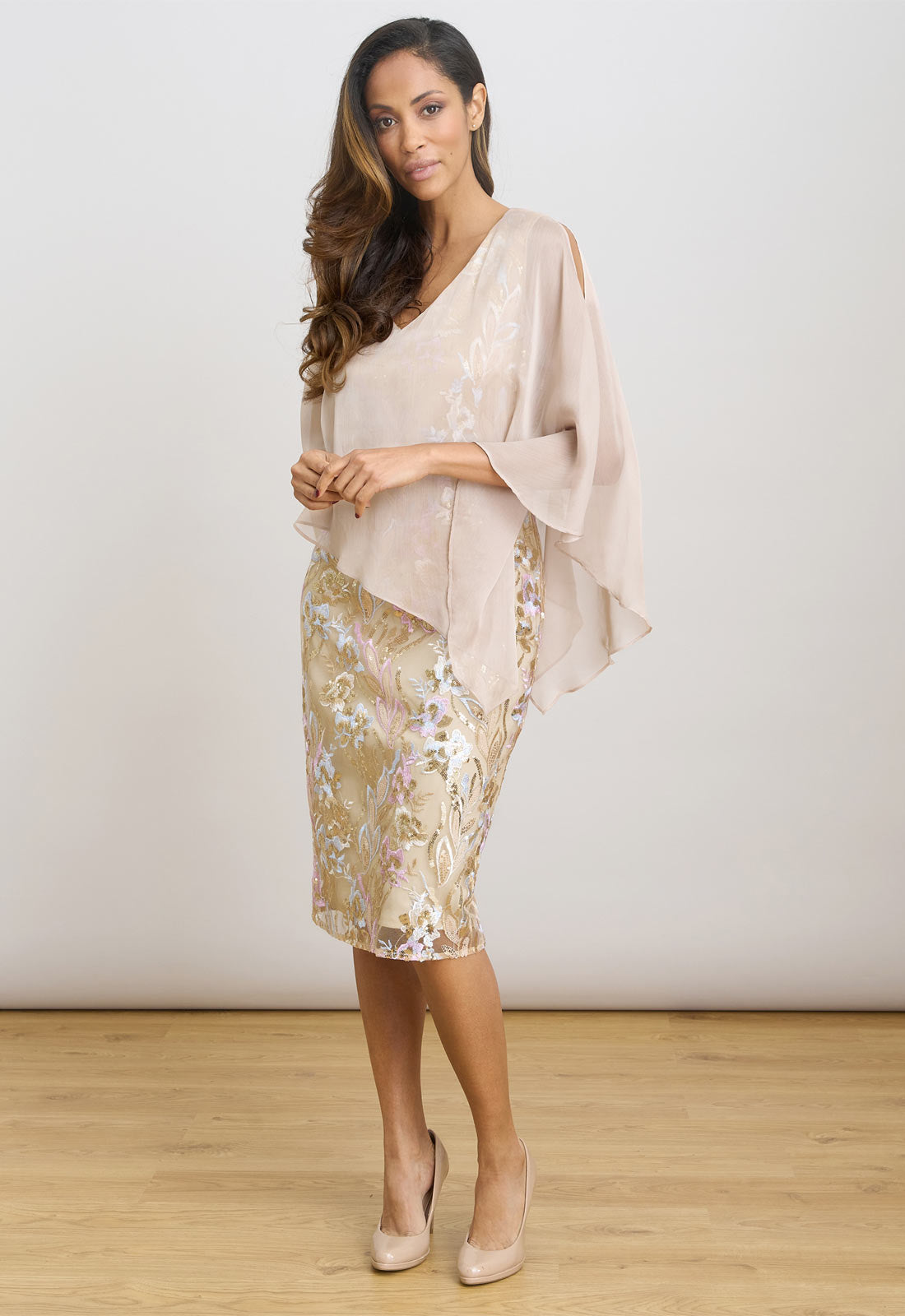 Woman wearing a beige top and floral skirt on a white background