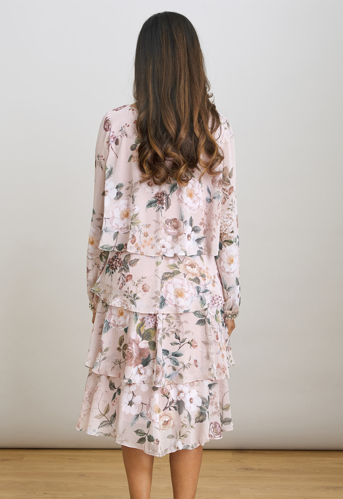 Woman wearing a floral dress with long sleeves against a plain background