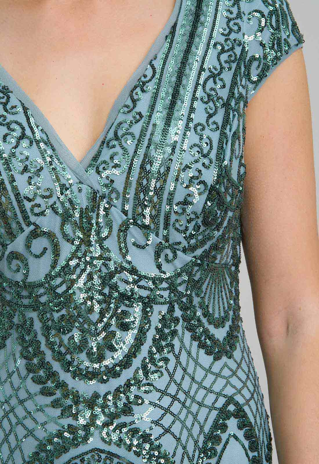 Close-up of a sequined dress with intricate patterns on a plain background