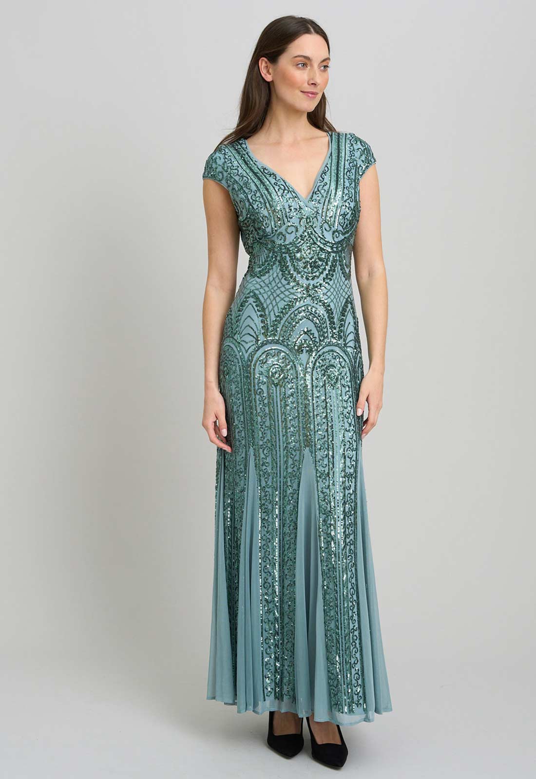 Woman wearing a teal patterned dress on a gray background
