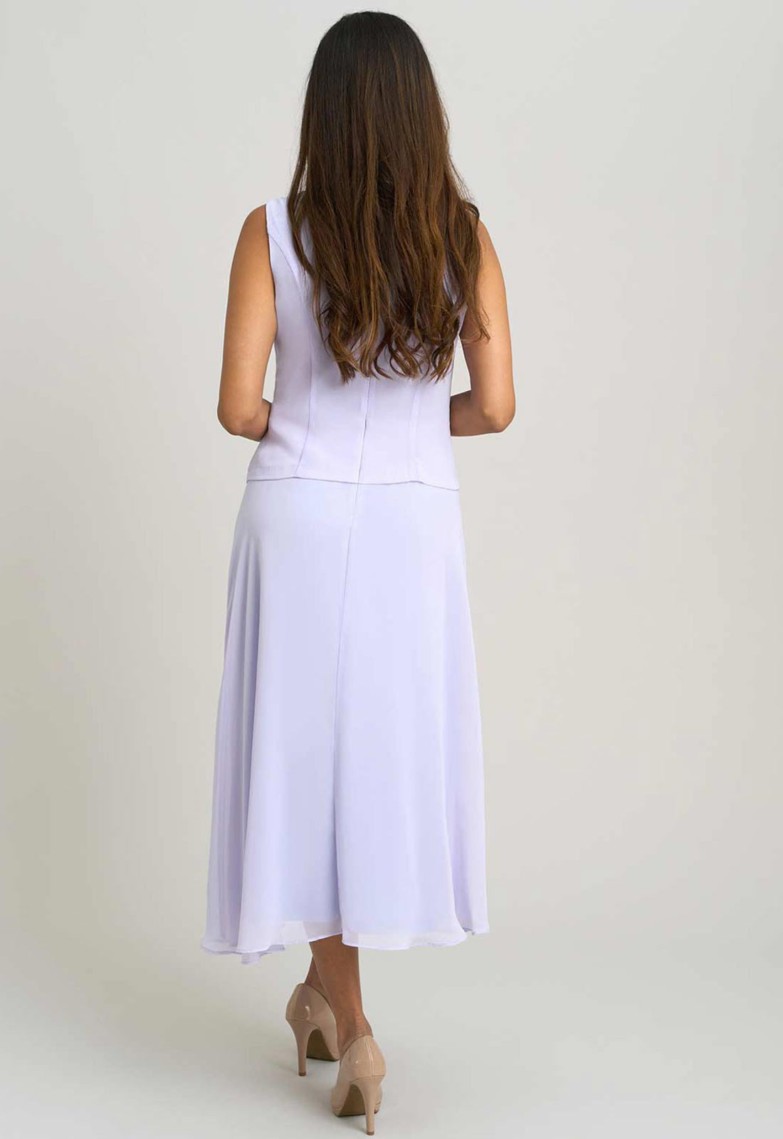 Woman wearing a white sleeveless top and skirt set on a plain background