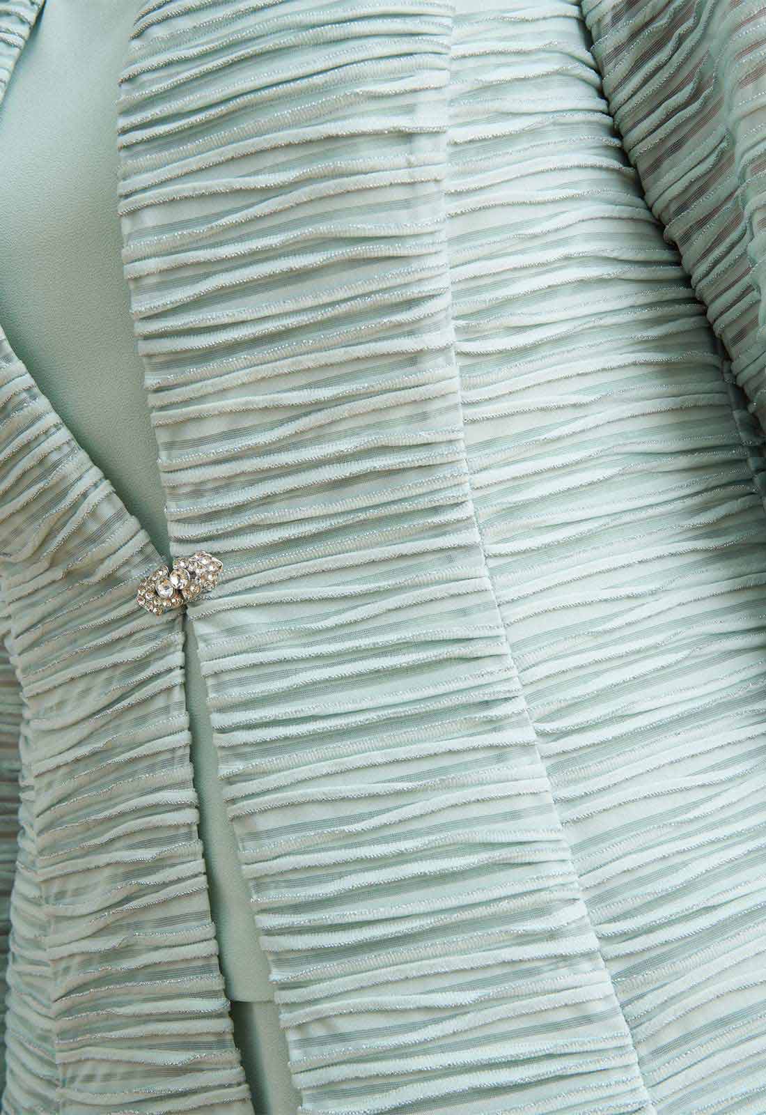 Close-up of a textured fabric with a brooch on a light background