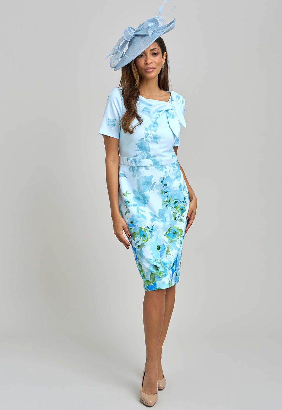 Woman wearing a light blue floral dress and matching hat on a gray background
