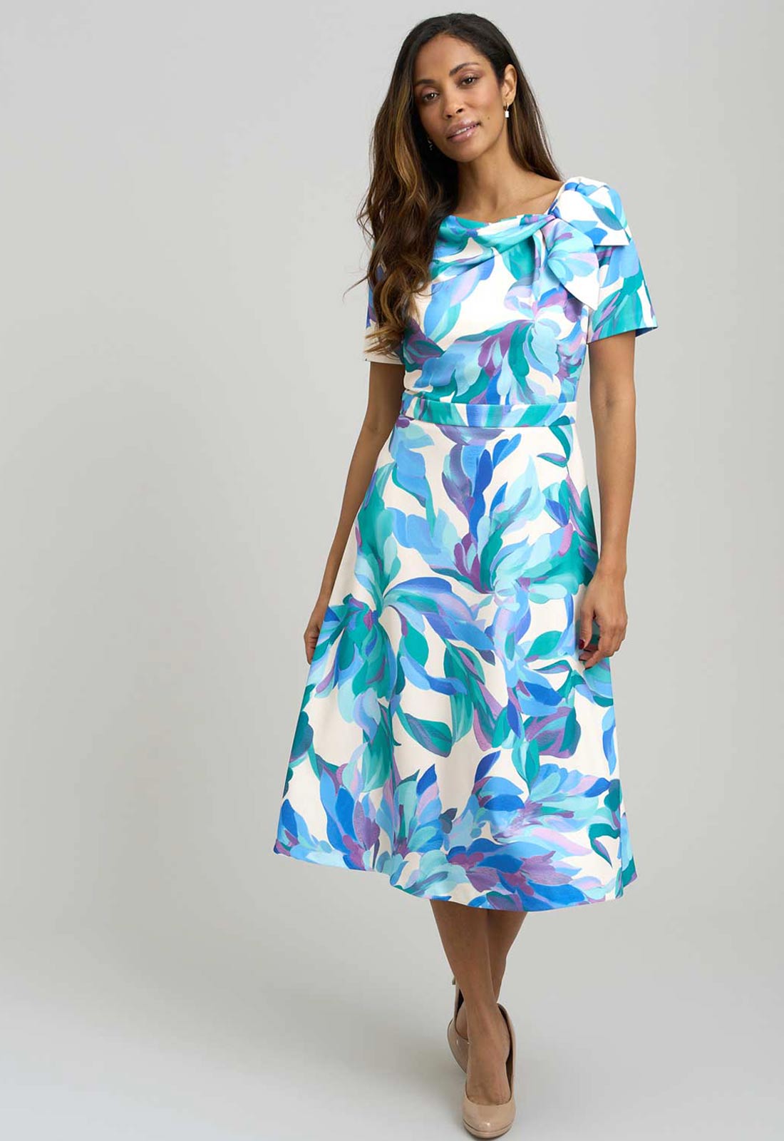 Woman wearing a colorful dress with abstract pattern on a plain background
