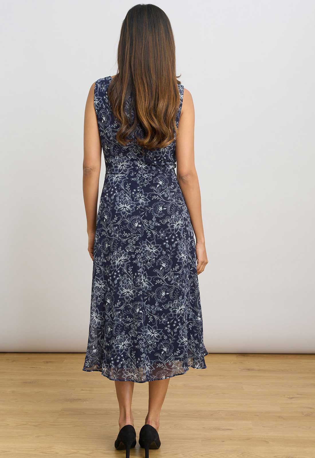 Woman wearing a navy floral dress against a plain background