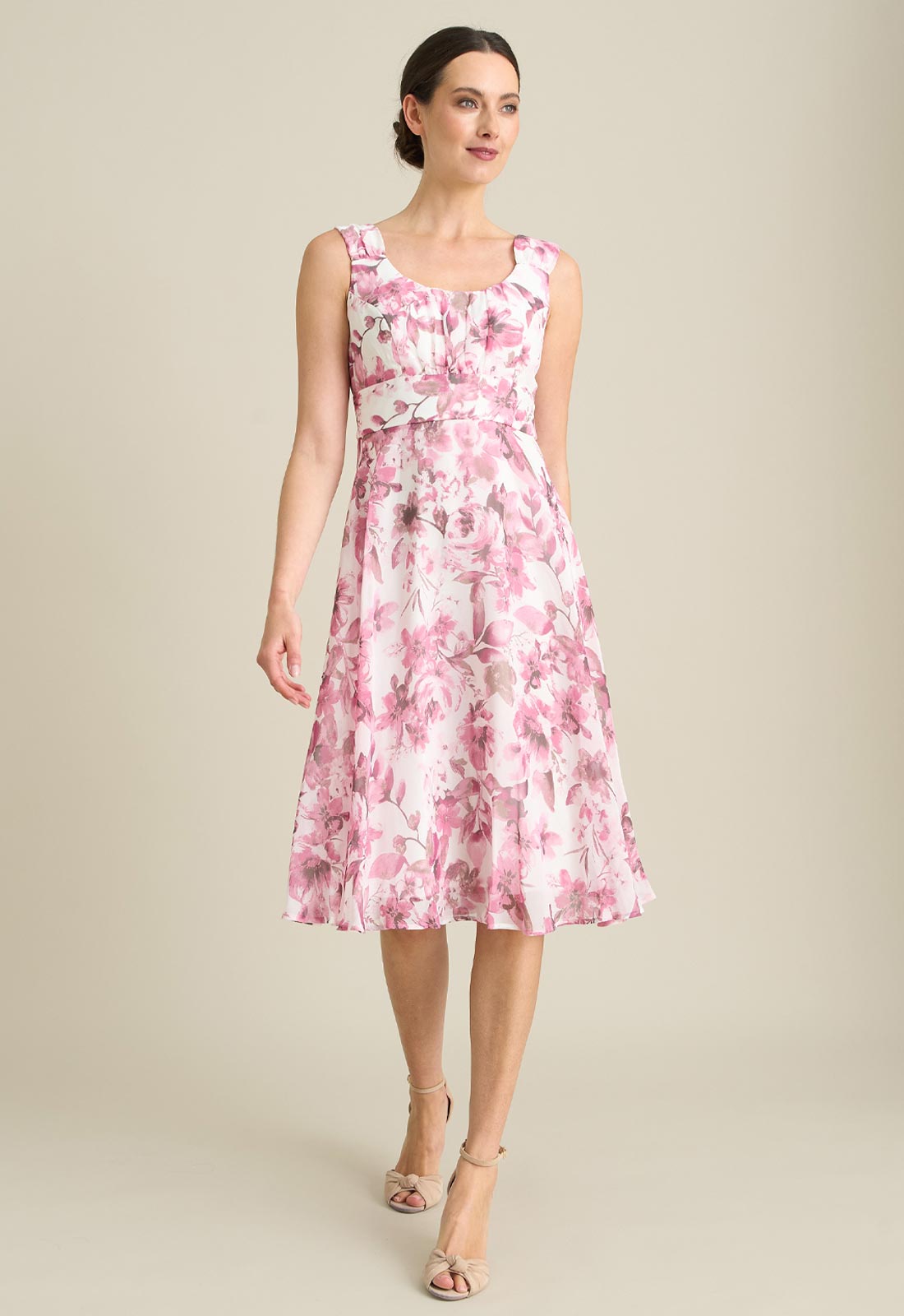Woman wearing a pink floral dress against a beige background