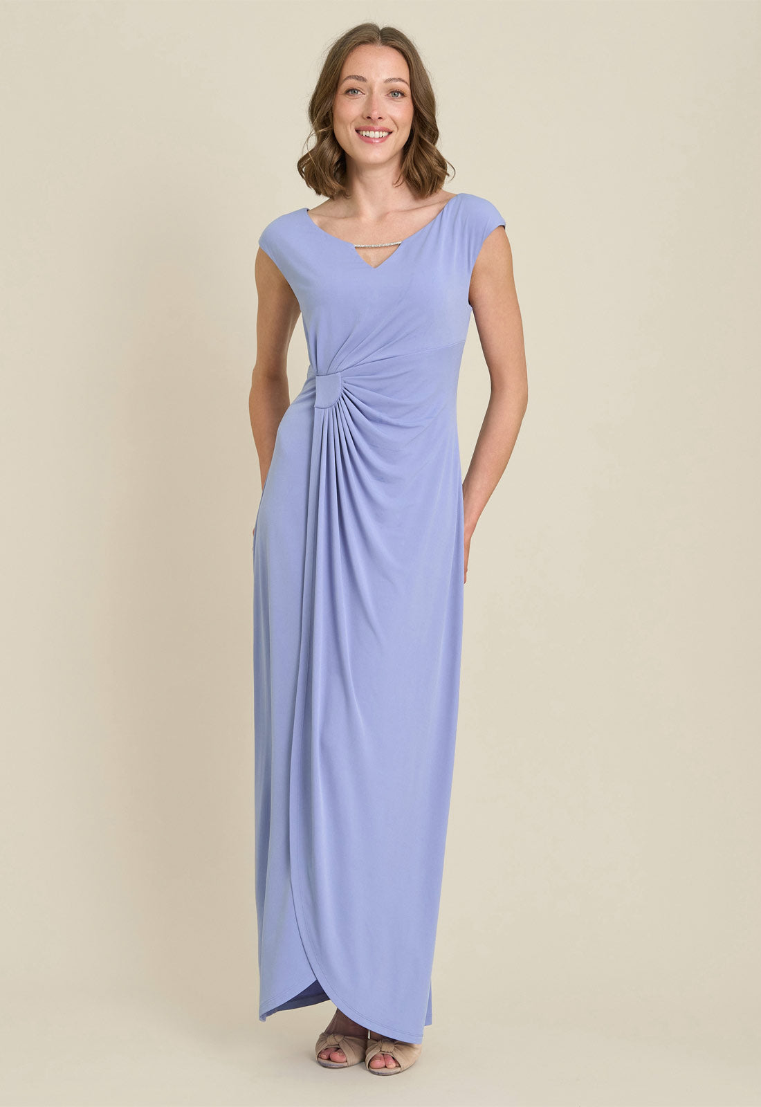 Woman wearing a long light blue dress against a beige background