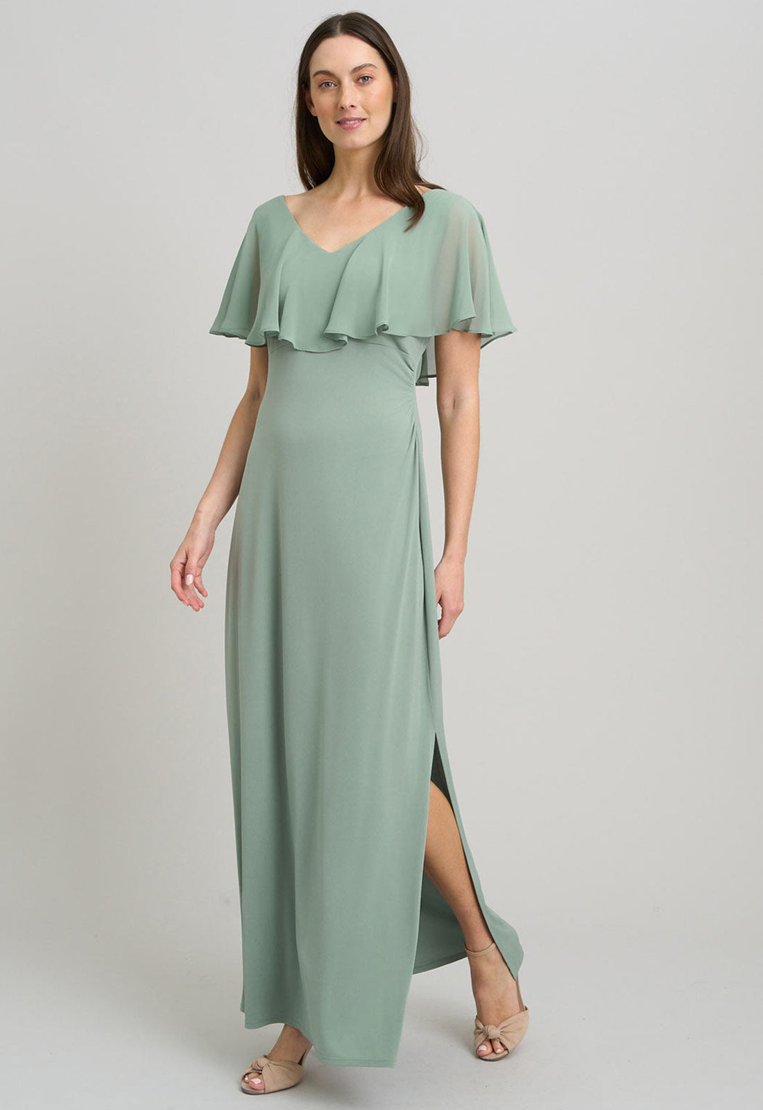 Woman wearing a green dress with ruffled sleeves on a light gray background