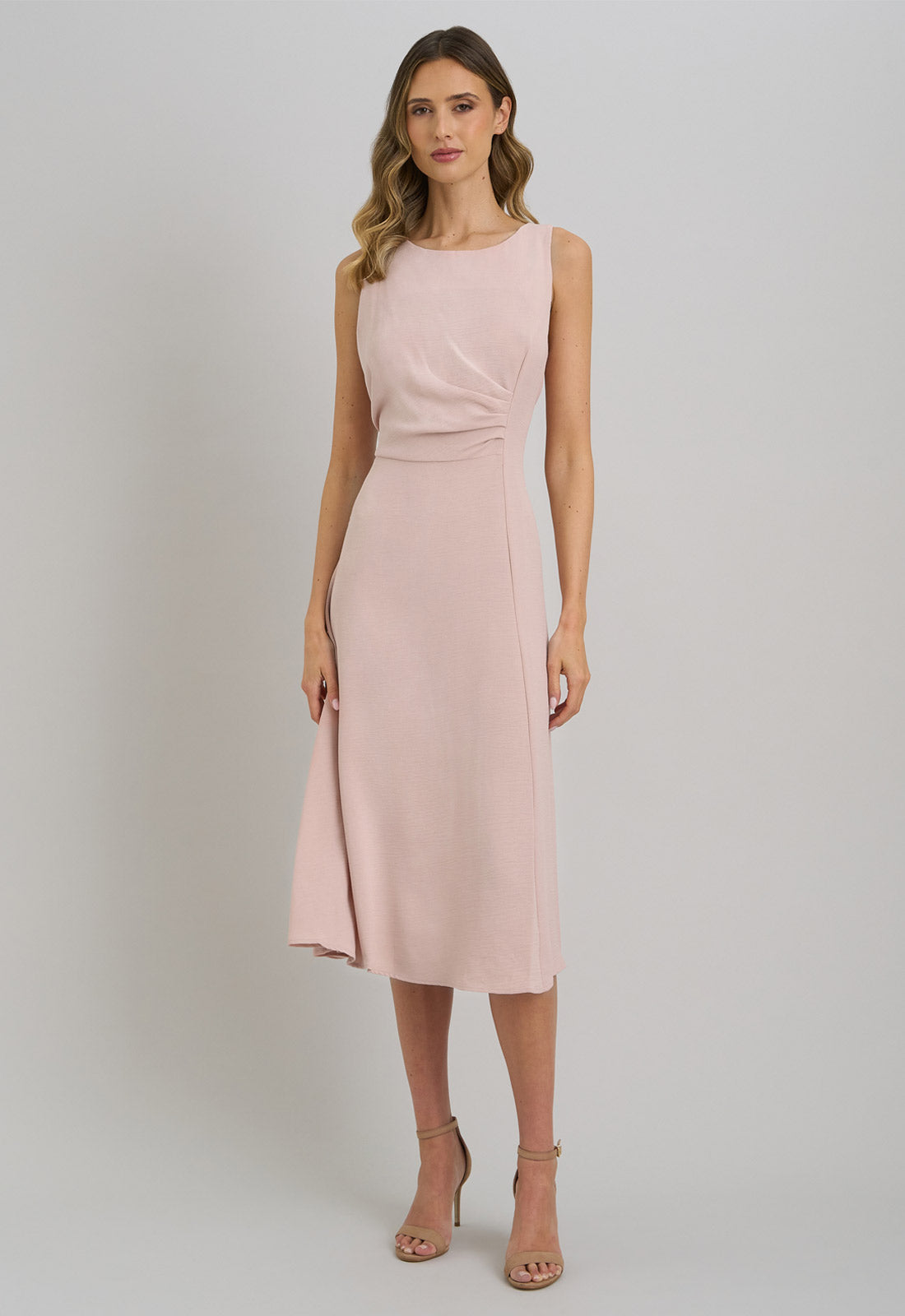 Woman wearing a pink sleeveless dress on a plain background