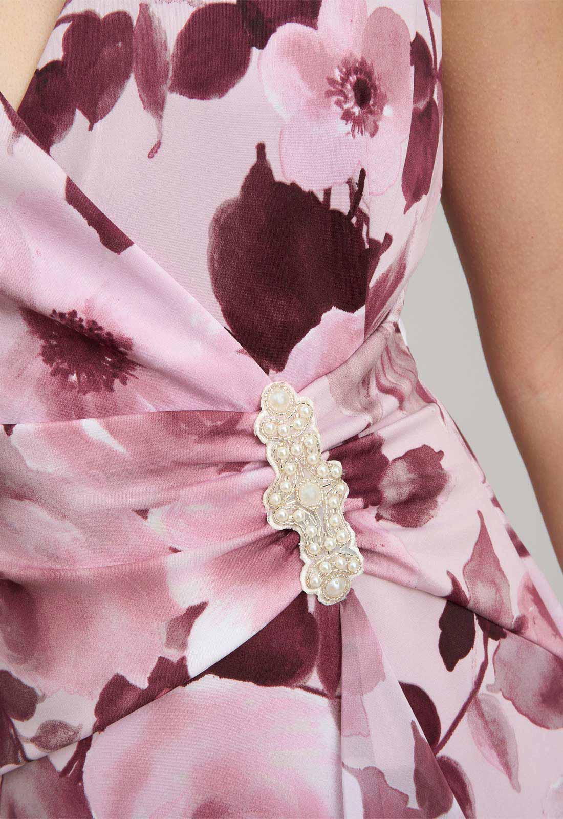 Close-up of a floral dress with a decorative brooch.