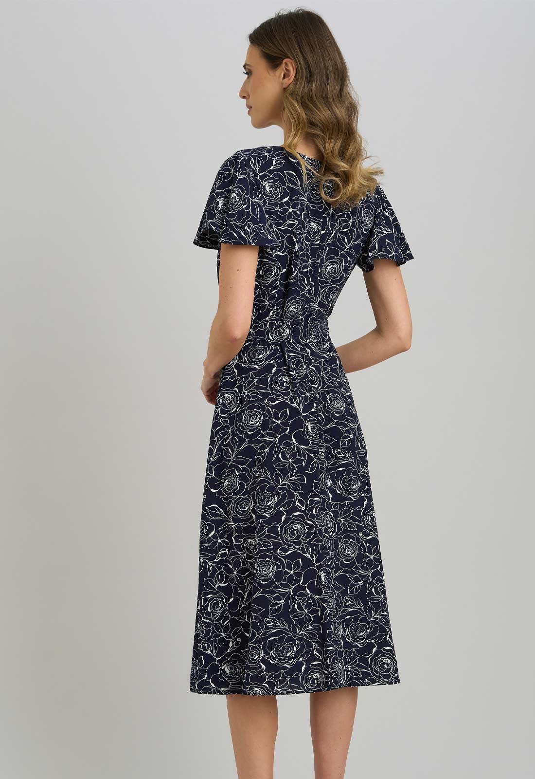 Woman wearing a navy floral dress against a plain background