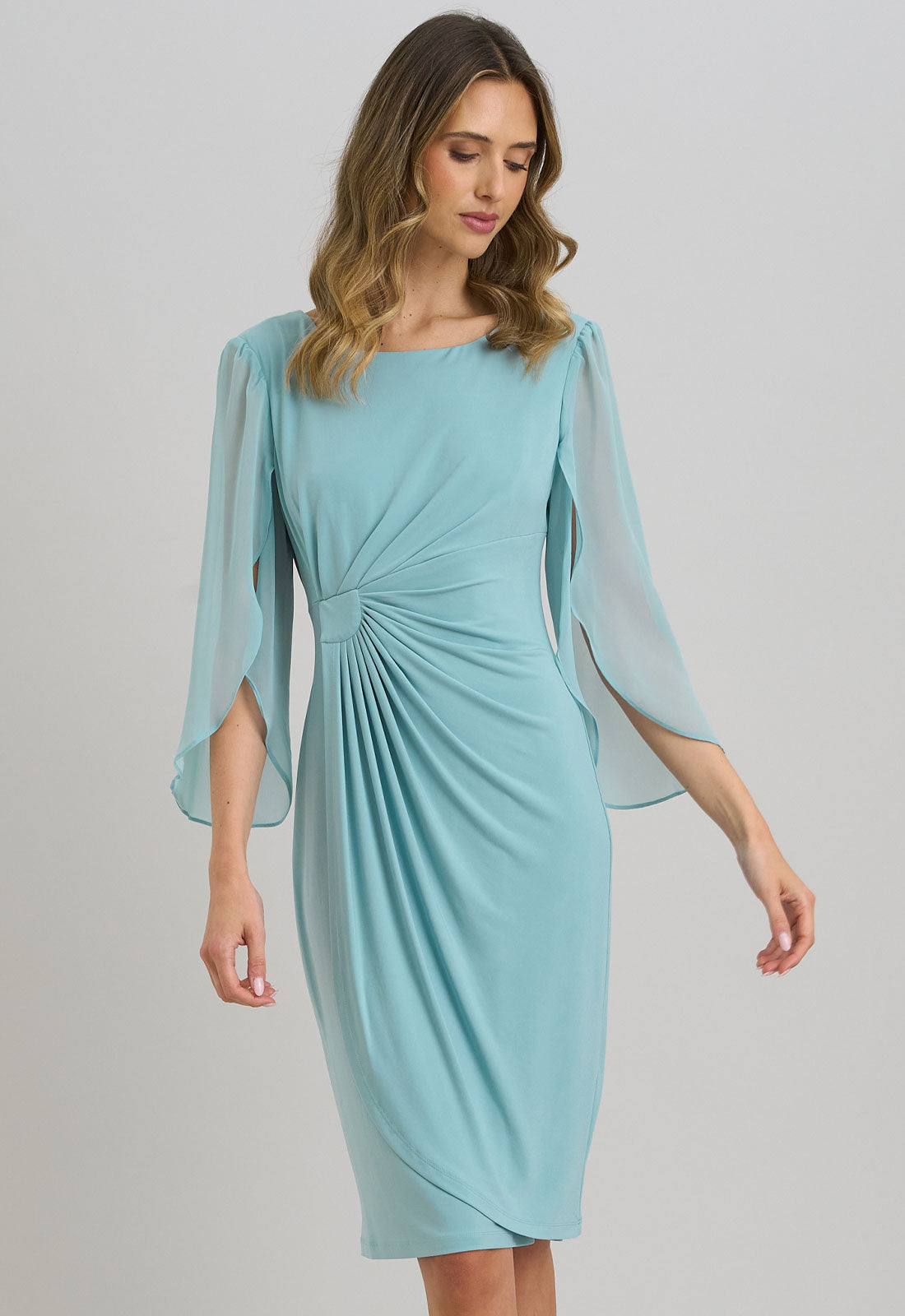 Woman wearing a light blue dress with sheer sleeves on a gray background