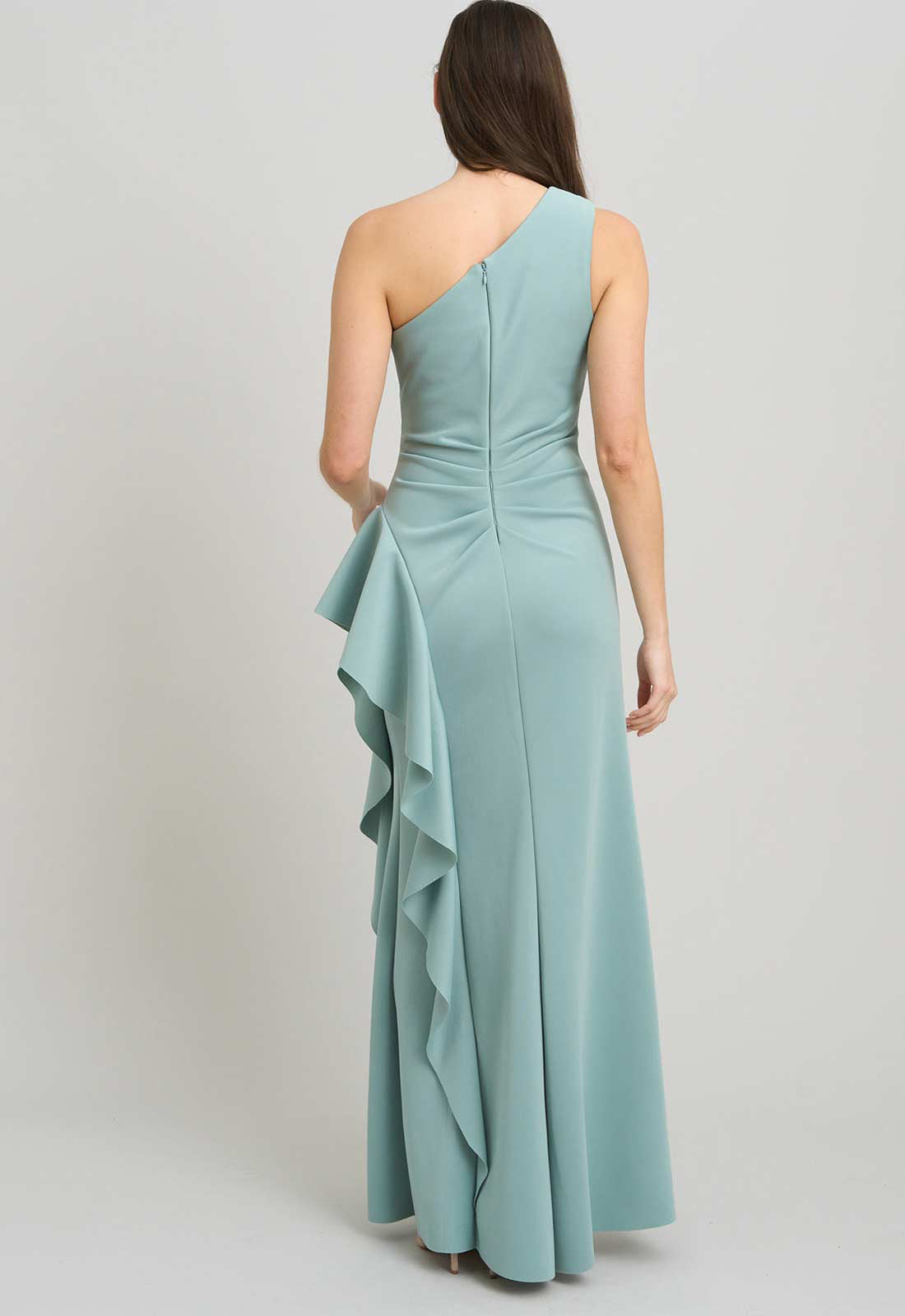 Woman wearing a light blue one-shoulder dress with ruffled details on a plain background