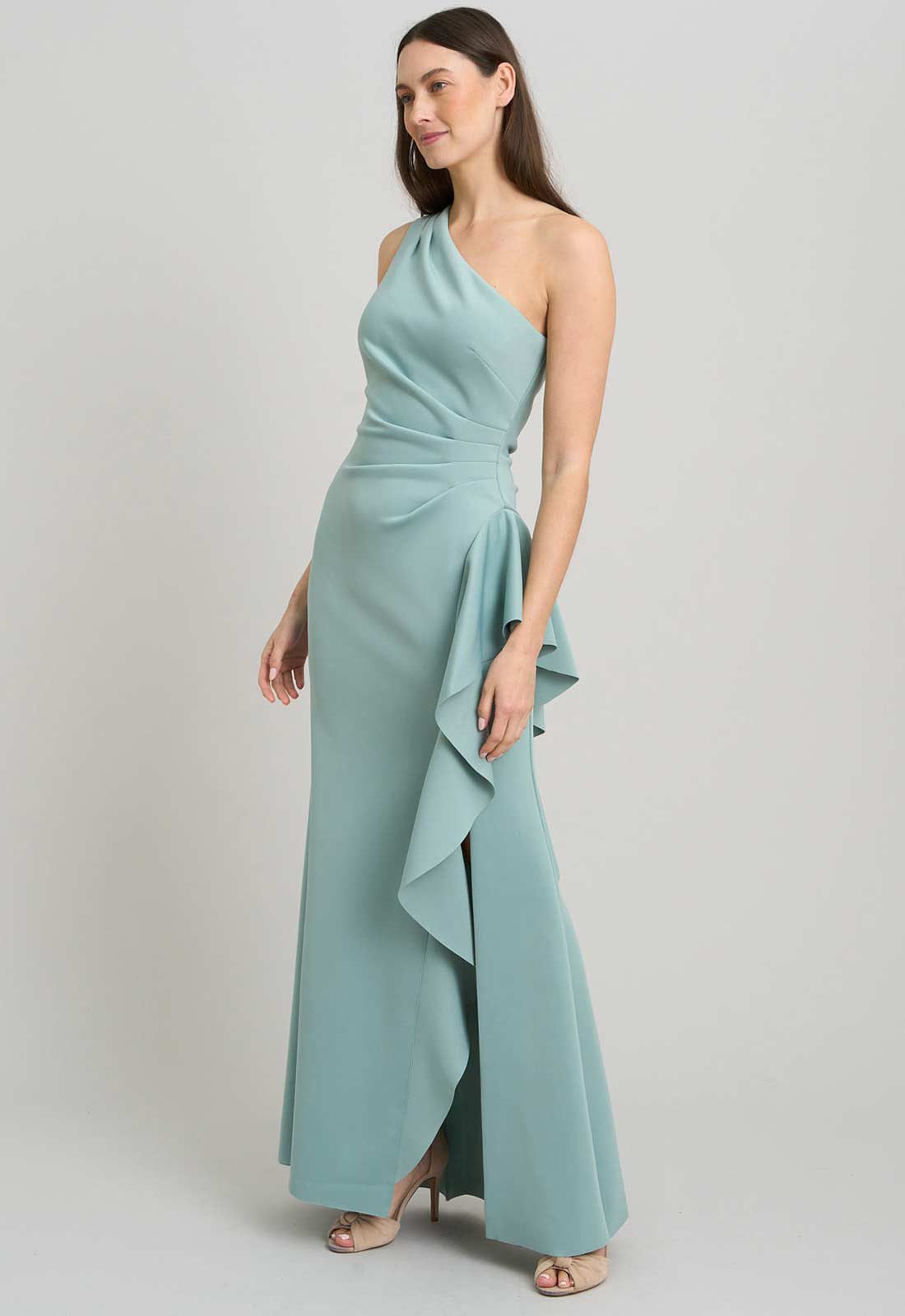 Woman wearing a light blue one-shoulder dress with a ruffled skirt on a plain background