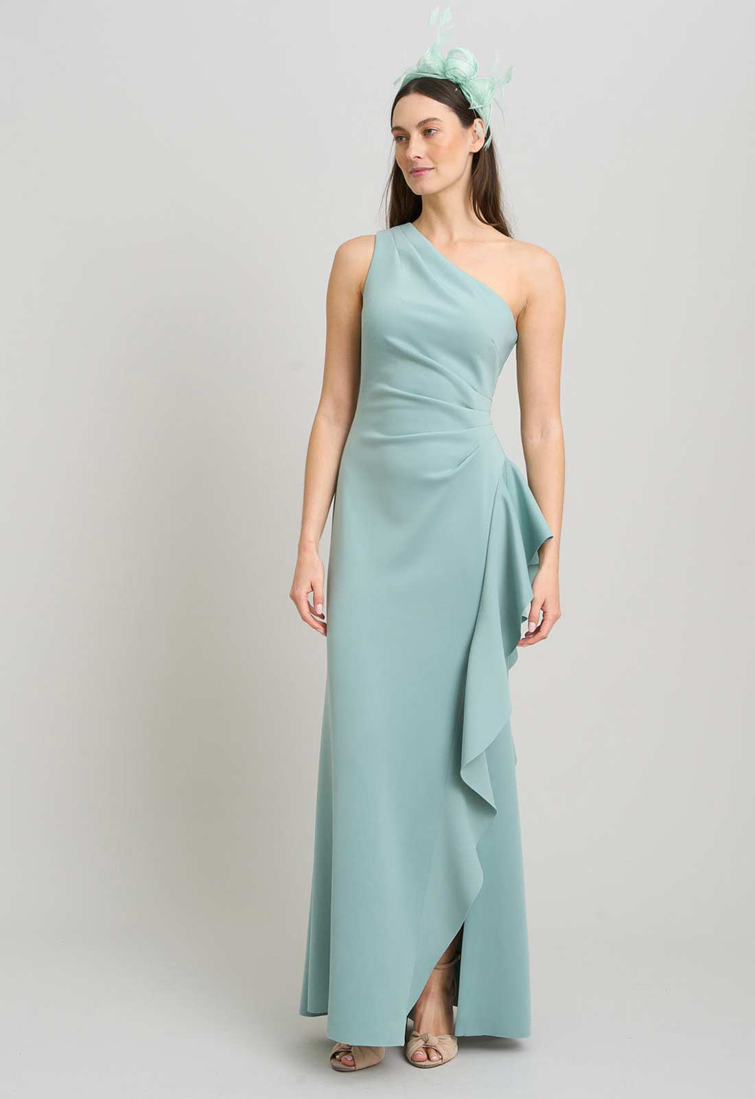 Woman wearing a light blue one-shoulder dress with a plain background