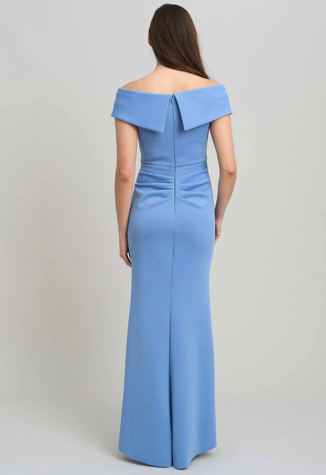 Woman wearing a blue off-shoulder gown on a plain background