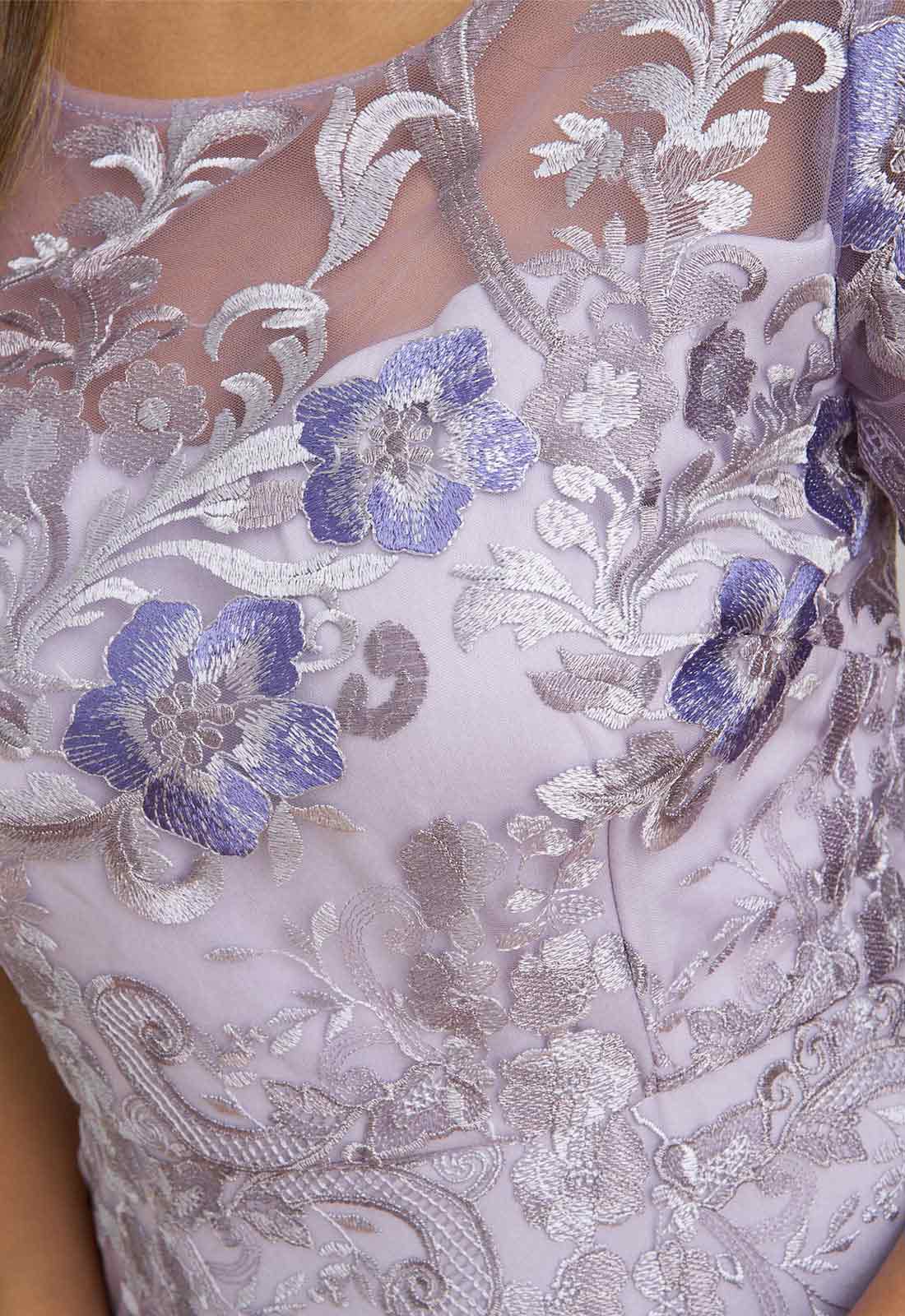 Close-up of a lace fabric with floral patterns and blue flowers.