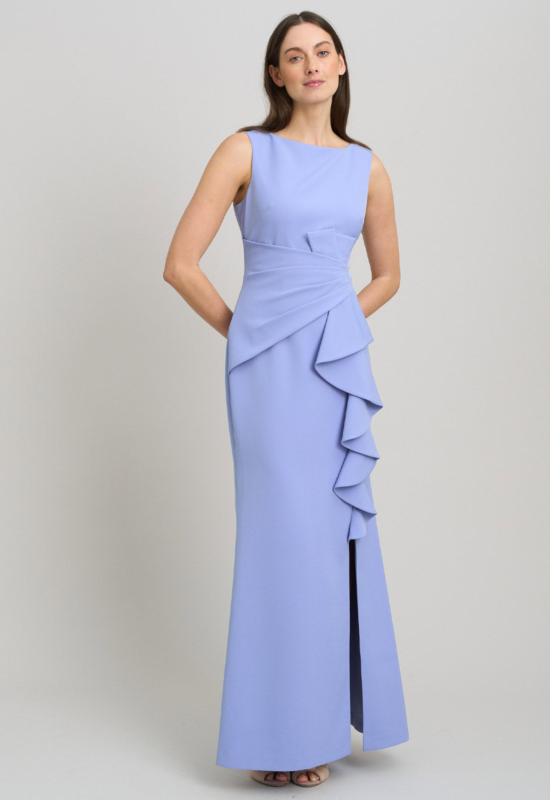 Woman wearing a light blue evening gown with ruffled details on a gray background