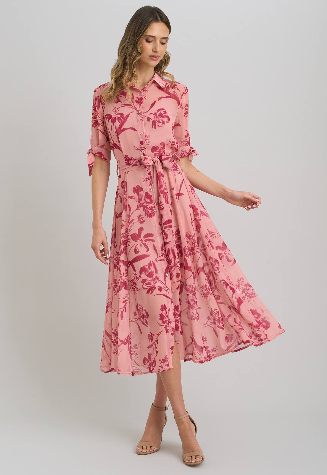 Woman wearing a pink floral dress on a plain background