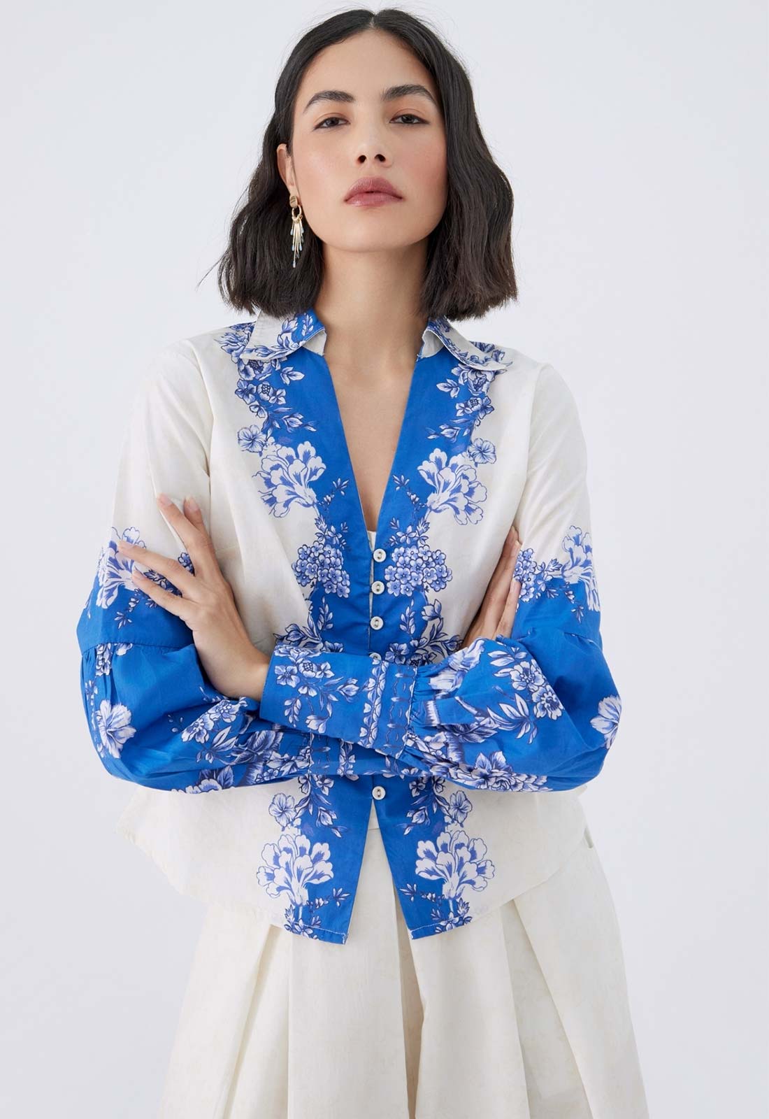 Woman wearing a blue floral blouse over a white shirt with a white background