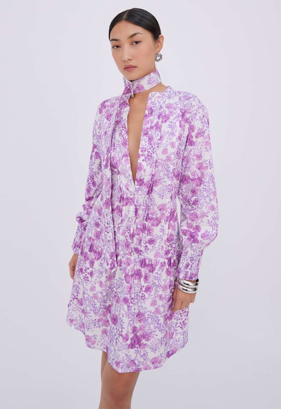 Woman wearing a purple floral dress on a light gray background