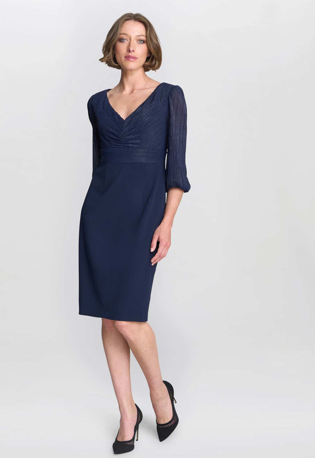 Woman wearing a navy blue dress with a plain background