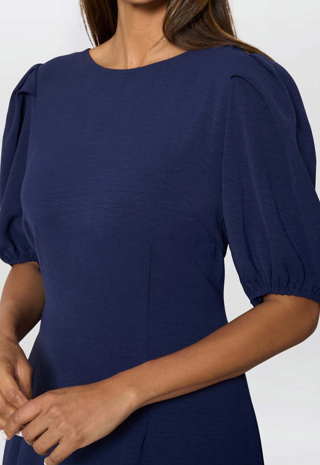 Navy blue dress with puff sleeves worn by a person on a white background