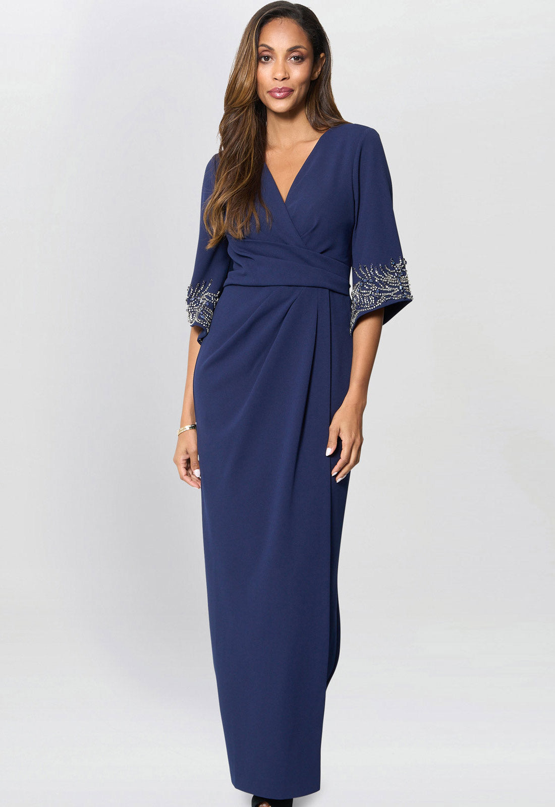 Woman wearing a blue dress with embroidered sleeves on a white background