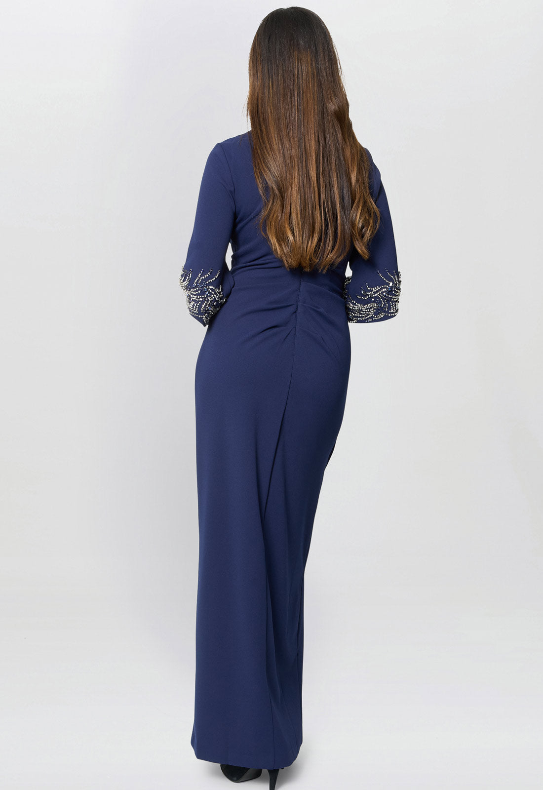 Woman wearing a blue dress with intricate designs on a white background