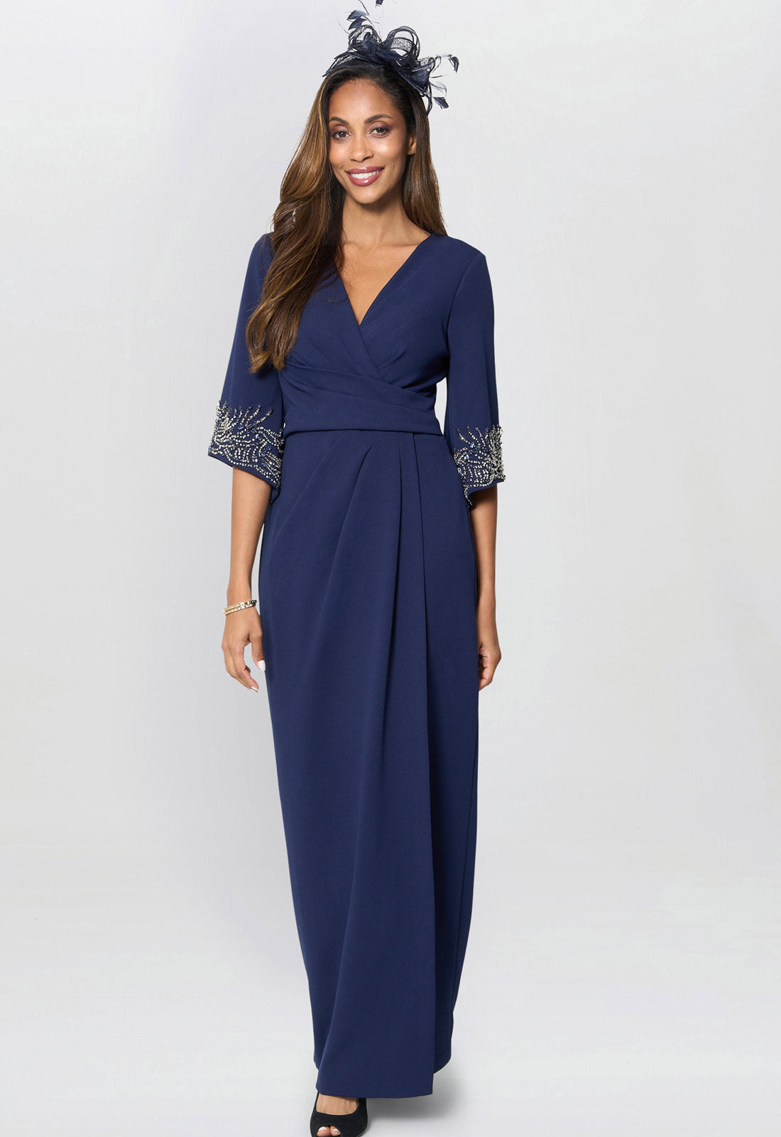 Woman wearing a navy blue dress with lace cuffs on a white background
