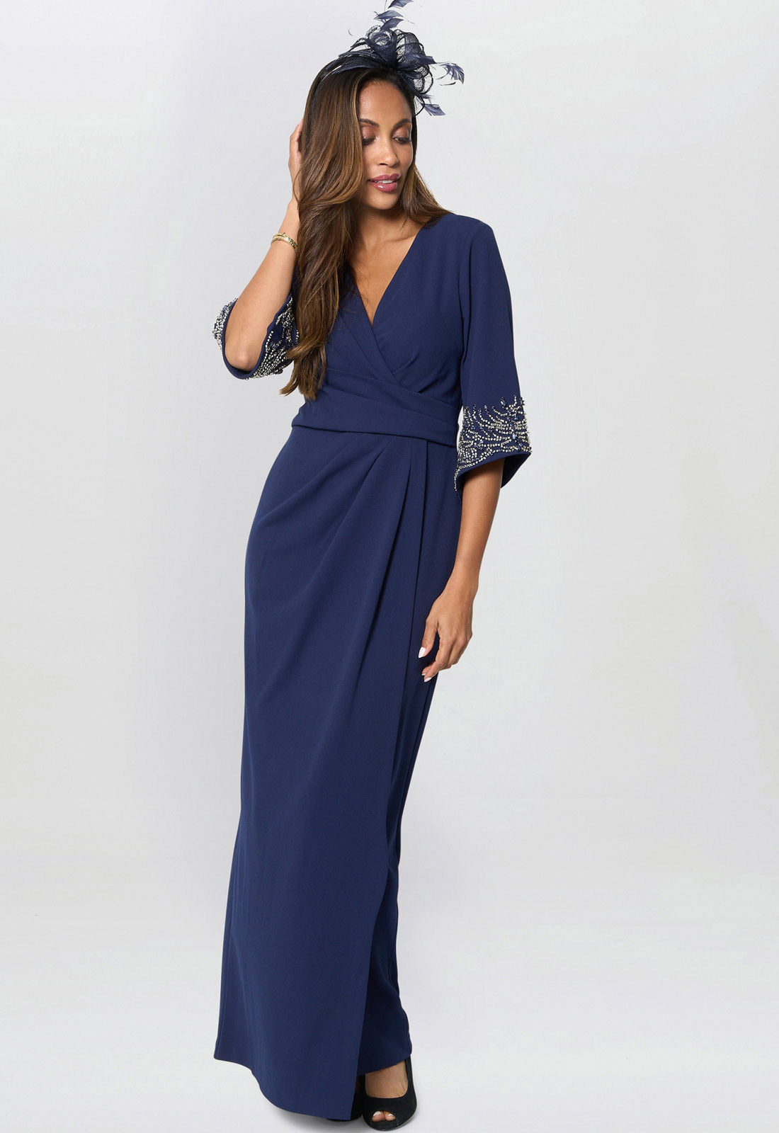 Woman wearing a navy blue dress with floral headpiece on a white background