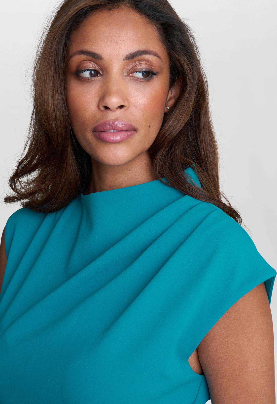Woman wearing a teal dress against a white background