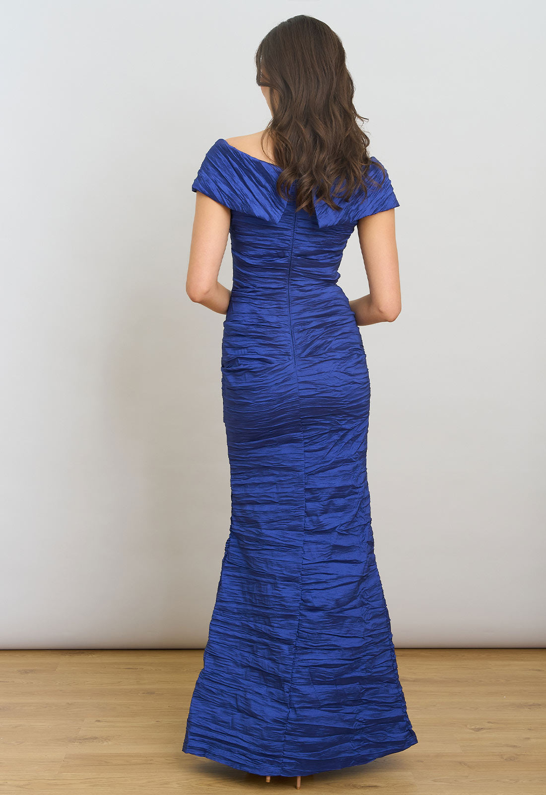 Woman wearing a blue evening gown against a plain background