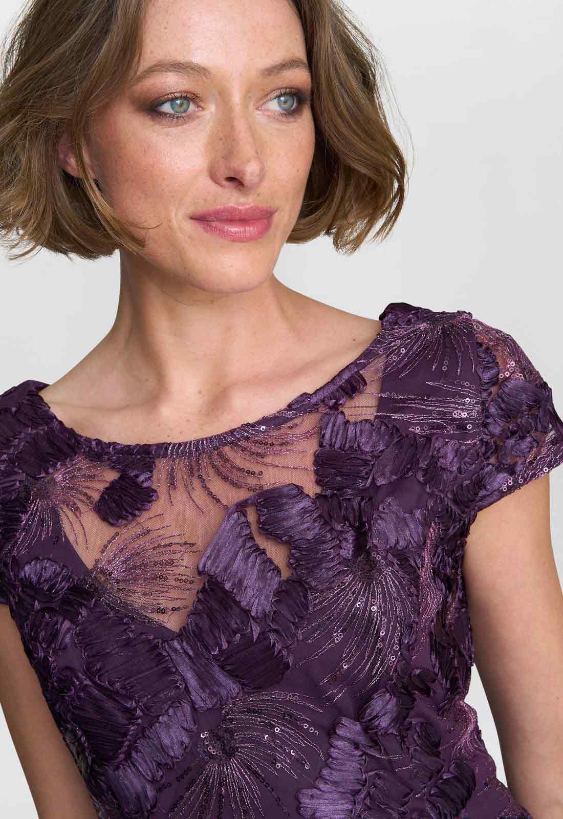 Woman wearing a purple lace dress against a plain background