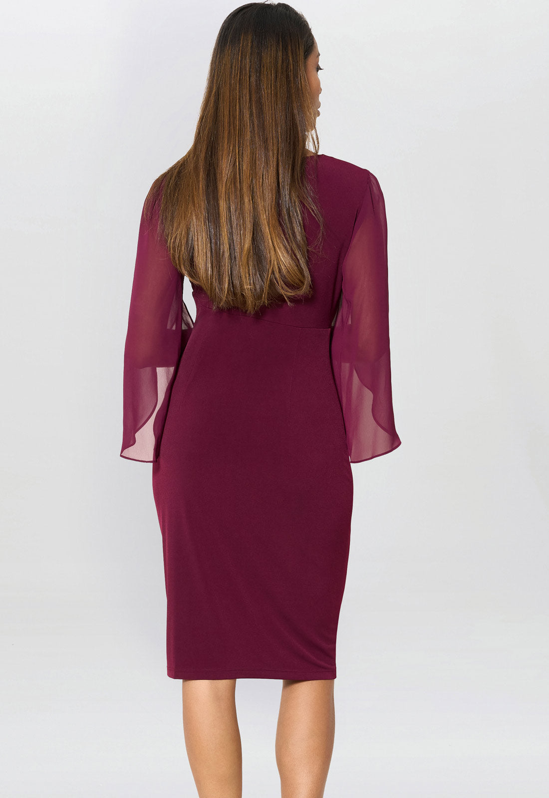 Woman wearing a burgundy dress with sheer sleeves on a white background