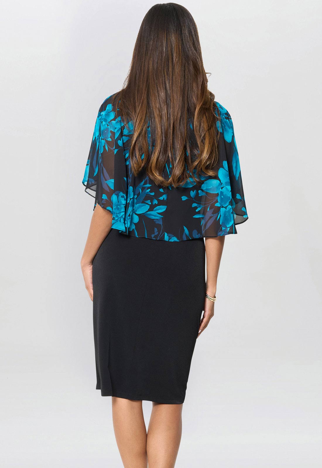 Woman wearing a black dress with a blue floral top against a white background