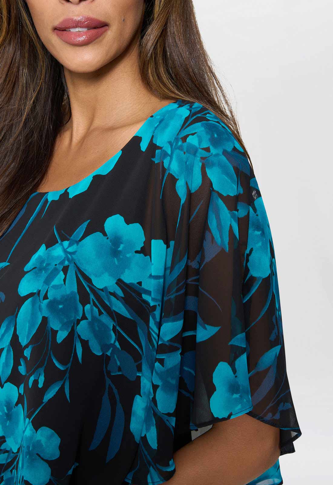 Woman wearing a black and blue floral blouse against a white background