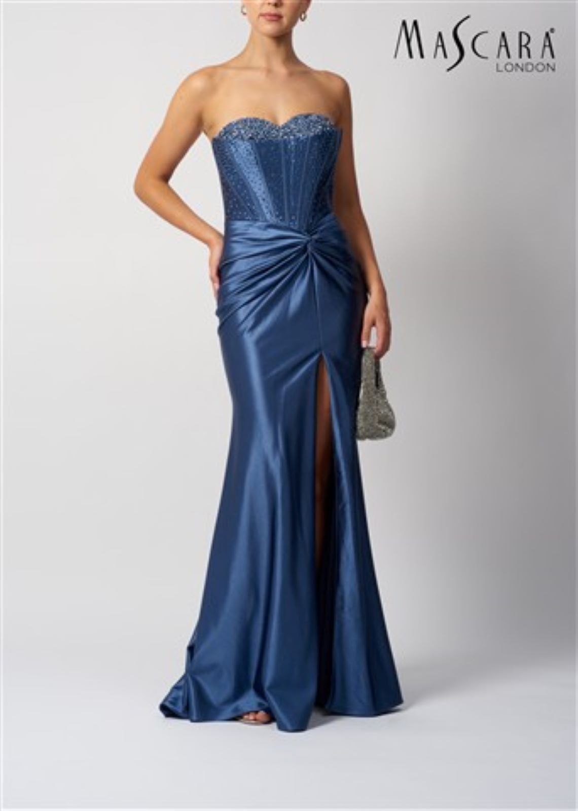 Woman wearing a blue strapless gown with a slit on a white background, branded 'Mascara London'.
